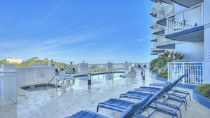 A rooftop pool area with lounge chairs, a pool, and a building with balconies. - Horizon Penthouse 18, Lovely Condo in Myrtle Beach (Myrtle Beach)