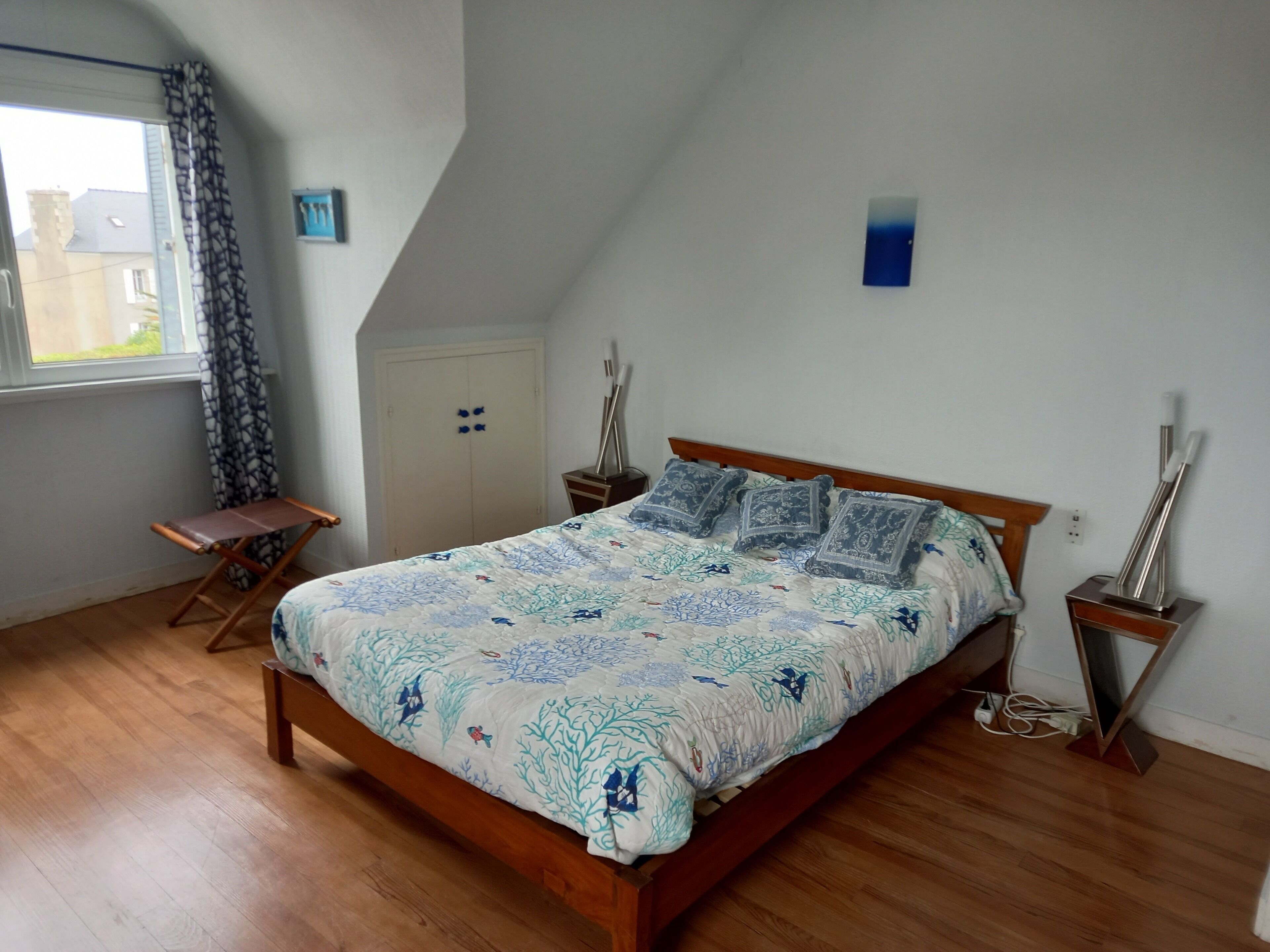 Una camera da letto con un letto di legno, un armadio, un tavolino e una finestra con tende.