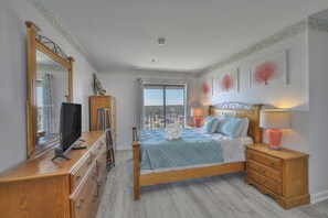 A bedroom with a large bed, a dresser, a television on the dresser, and a window with a view. - MB Resort Renaissance 514 - OV 2 Bedrooms (Myrtle Beach)