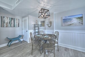 A dining area with a round table, six chairs, and a chandelier. - MB Resort Renaissance 514 - OV 2 Bedrooms (Myrtle Beach)