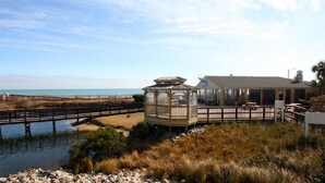 Una propiedad costera con un pabellón, un patio cubierto y vistas a la playa y al mar.