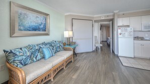 Ein Wohnzimmer mit einer Couch, einer Lampe und einem Bild an der Wand.