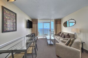 Enjoy a sea view from the balcony, with a dining table, sofa, and flat-screen TV in this comfortable room.