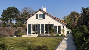 Ein modernes Haus mit weißer Fassade, rotem Dach und einer Zuwegung mit Kies, die zu einer überdachten Terrasse führt.