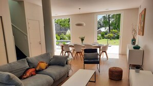 Ein modernes Wohnzimmer mit einem grauen Sofa, einem weißen Couchtisch und einem Essbereich mit Tisch und Stühlen.