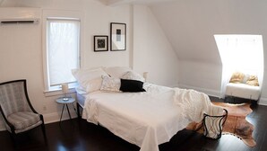 Une chambre à coucher avec un lit, une chaise, une petite table et une fenêtre.