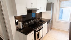 Une cuisine moderne avec des armoires blanches, un plan de travail noir, une cuisinière et un four encastré.