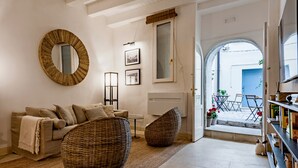 A living room with a sofa, wicker chairs, a mirror, and a bookshelf. - CharmSuites - charming flat in Ortigia (Siracusa)