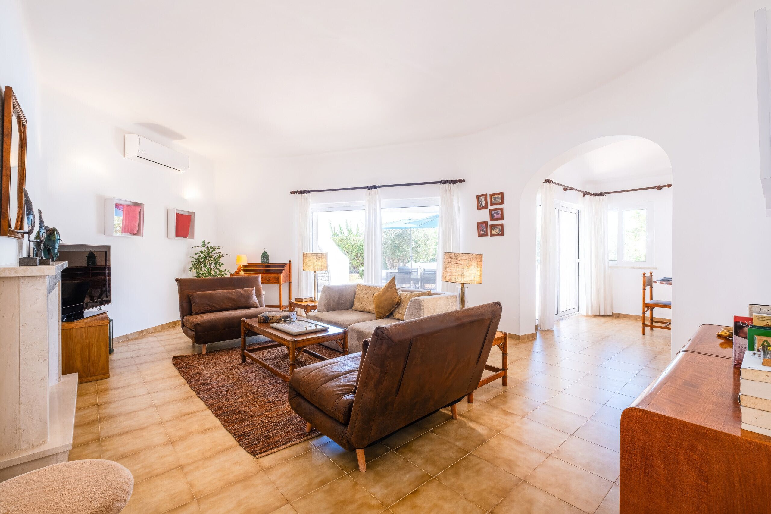 A spacious living room with a fireplace, a sofa set, a coffee table, and a dining area with a wooden table and chairs.