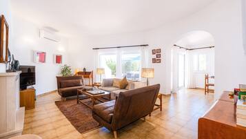 A spacious living room with a fireplace, a sofa set, a coffee table, and a dining area with a wooden table and chairs.