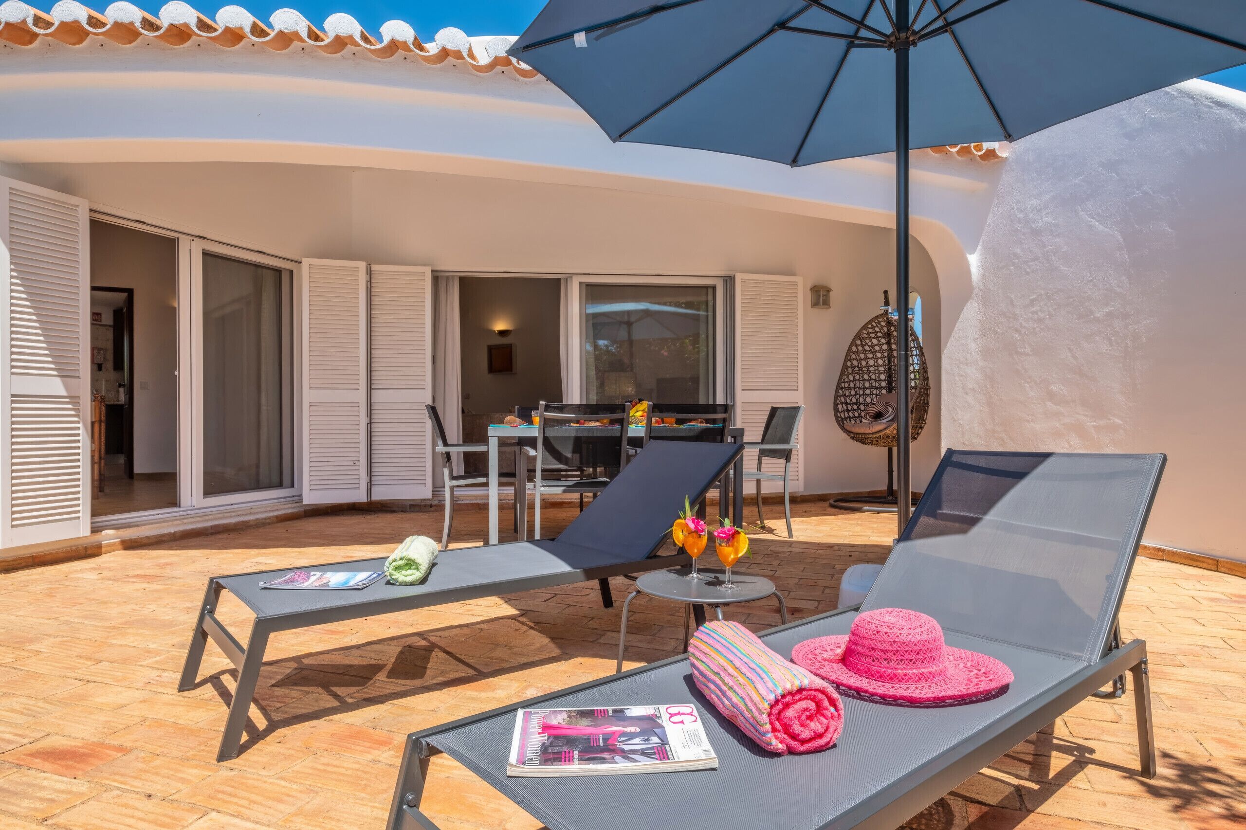 An outdoor patio with two lounge chairs, a table, and an umbrella.