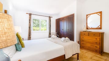 A bedroom with a bed, a dresser, a mirror, and a window with curtains.