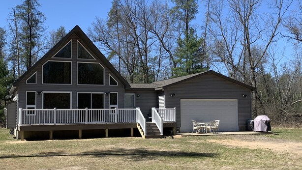 A two-story cabin with a large deck, a garage, and a covered outdoor seating area. - Perfect Getaway! Secluded Modern 3 Bedroom, 2 Bath Cabin on 12.5 Private Acres (Baldwin)