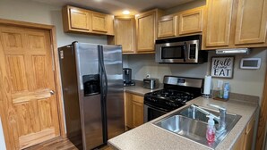 A modern kitchen with wooden cabinets, stainless steel appliances, a built-in microwave, and a granite countertop. - Perfect Getaway! Secluded Modern 3 Bedroom, 2 Bath Cabin on 12.5 Private Acres (Baldwin)