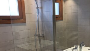 Un baño moderno con cabina de ducha de vidrio, un lavabo blanco y un espejo encima.