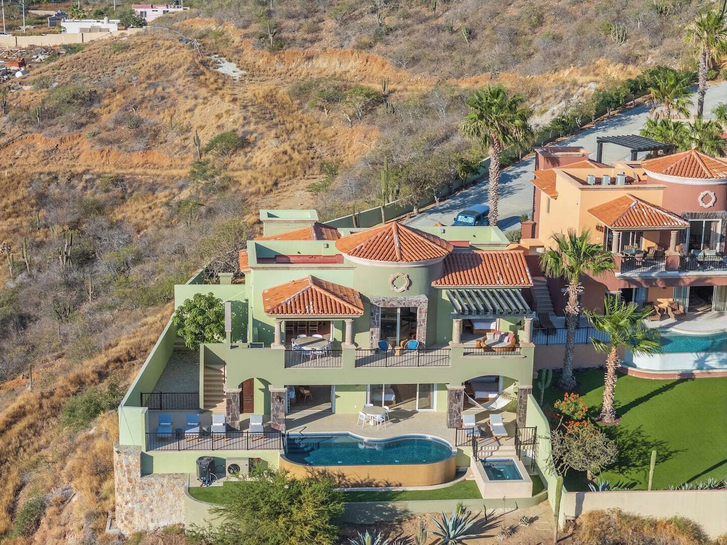 Una casa de varios pisos con piscina, mobiliario exterior y vistas del paisaje circundante.