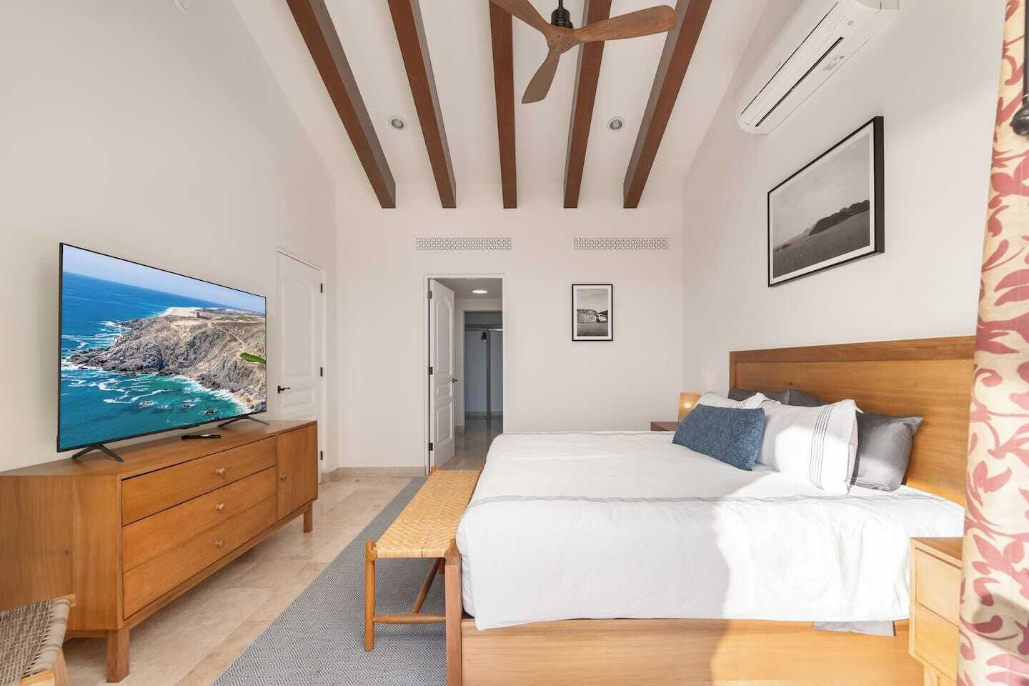 Un dormitorio con cama, televisor, muebles de madera y vista al océano.