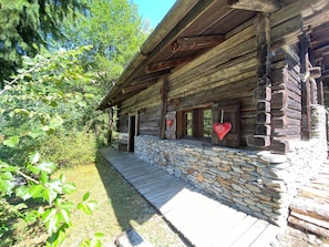 Una cabaña rústica de troncos con cimientos de piedra, porche de madera y decoraciones con forma de corazón.
