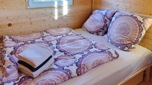 A wooden cabin room with a bed, a window, and a wall-mounted light fixture. - Gemütlicher Schäferwagen in der Eifel (Nettersheim)