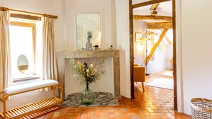 Une pièce avec un banc, un miroir, une cheminée et un plafond avec une poutre en bois.