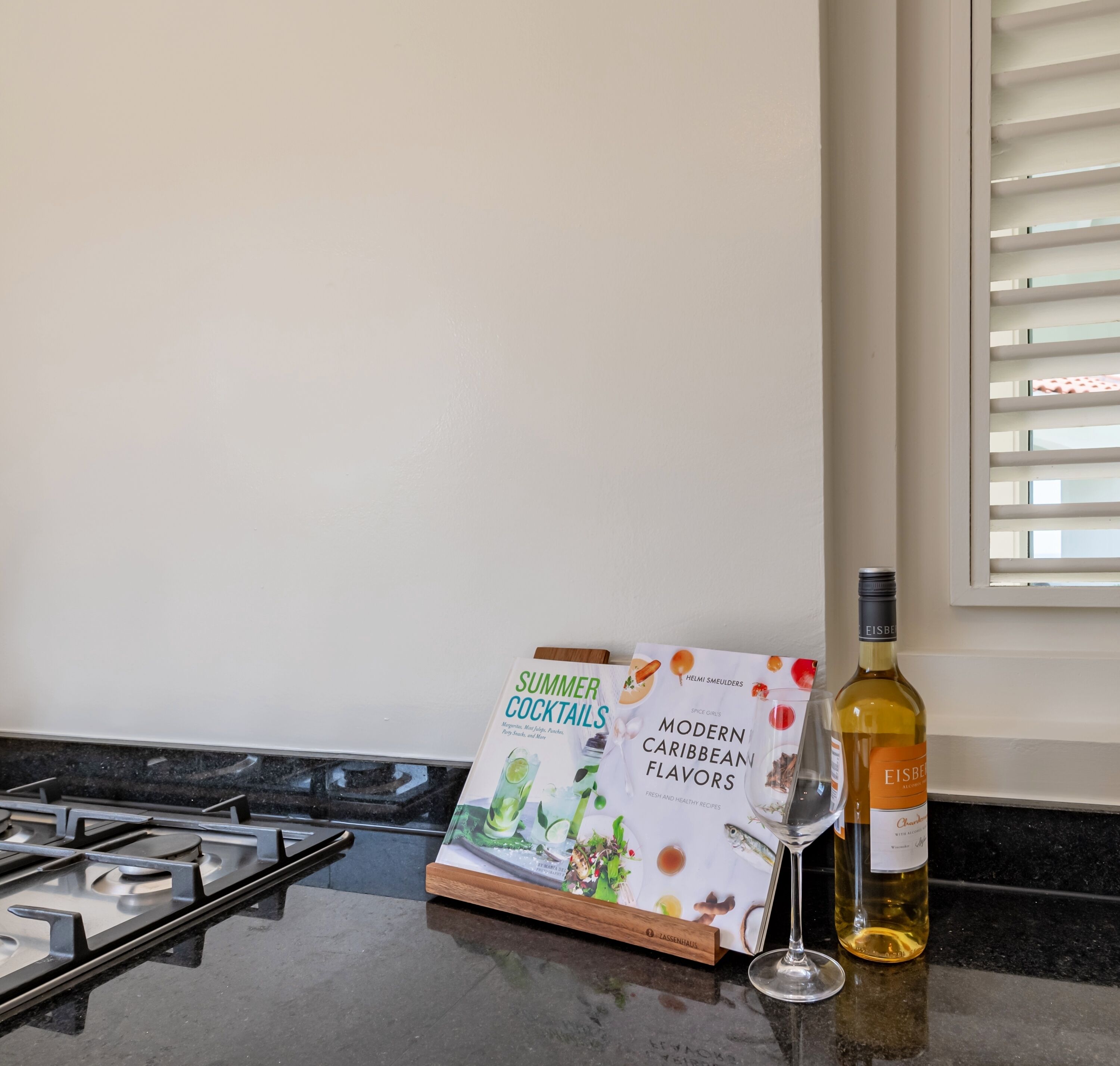 A kitchen counter with a cookbook titled 'Summer Cocktails' and a bottle of Eisberg wine.