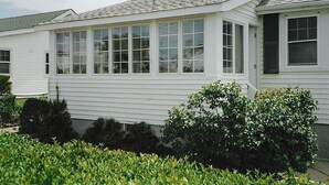 Ein weißes Einfamilienhaus mit einer Veranda und großen Fenstern.