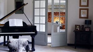 Ein Flügel in einem geräumigen Zimmer mit einer Kristallleuchtre, einem Klavierhocker und einem flauschigen Teppich.