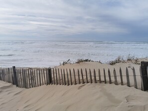 A sandy beach with a wooden fence and ocean waves.