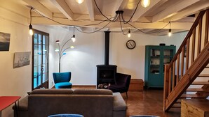 Una sala de estar acogedora con un sofá, sillones, chimenea y una escalera.