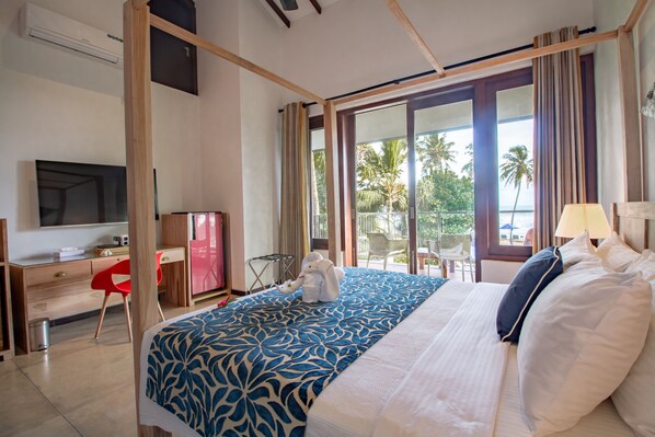 A hotel room with a bed, a desk, a television, and a view of palm trees. - Parangi Weligama Bay (Weligama)