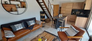 Una sala de estar moderna con un sofá de cuero, una mesa de centro y un comedor con taburetes.