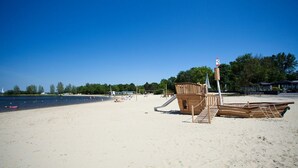 A sandy beach with a wooden play structure and a lifeguard tower.