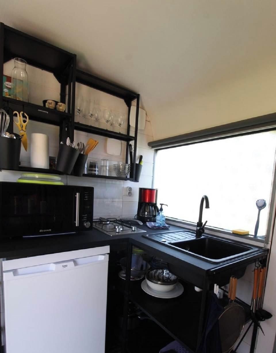 A compact kitchen with a microwave, sink, and a window for natural light.