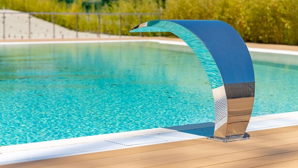 A swimming pool with a curved edge and a wooden deck. - Michelangelo - Borghetto Santo Spirito (Borghetto Santo Spirito)