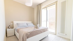 A bedroom with a bed, bedside table, and a window with blinds. - Michelangelo - Borghetto Santo Spirito (Borghetto Santo Spirito)