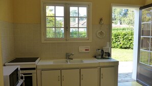 Una cocina con un amplio ventanal, armarios blancos y un fregadero.