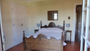 Un dormitorio con una cama de madera, dos mesitas de noche y una puerta.