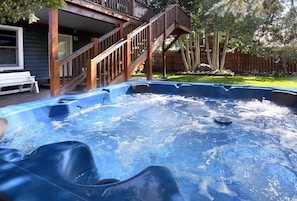 Un jacuzzi con terraza de madera y escaleras que llevan a una casa.