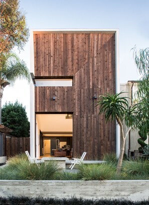 A modern house with a wooden exterior, a visible kitchen area, and outdoor seating. - Modern Serenity in the Heart of "Corona del Mar" (Newport Beach)