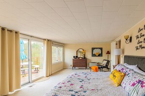 Un dormitorio con cama, cómoda, silla, escritorio y balcón con mobiliario exterior.