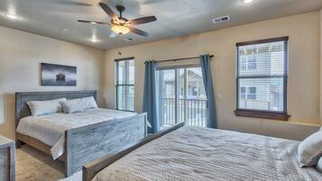 A bedroom with two beds, a ceiling fan, and large windows with curtains.
