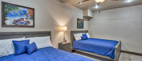 A hotel room with two beds, a ceiling fan, and artwork on the walls.