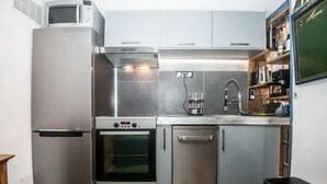Cocina compacta equipada con refrigerador, horno, lavavajillas y microondas.
