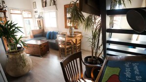 Una sala de estar acogedora con un sofá, sillas, una mesa de centro y plantas en macetas.