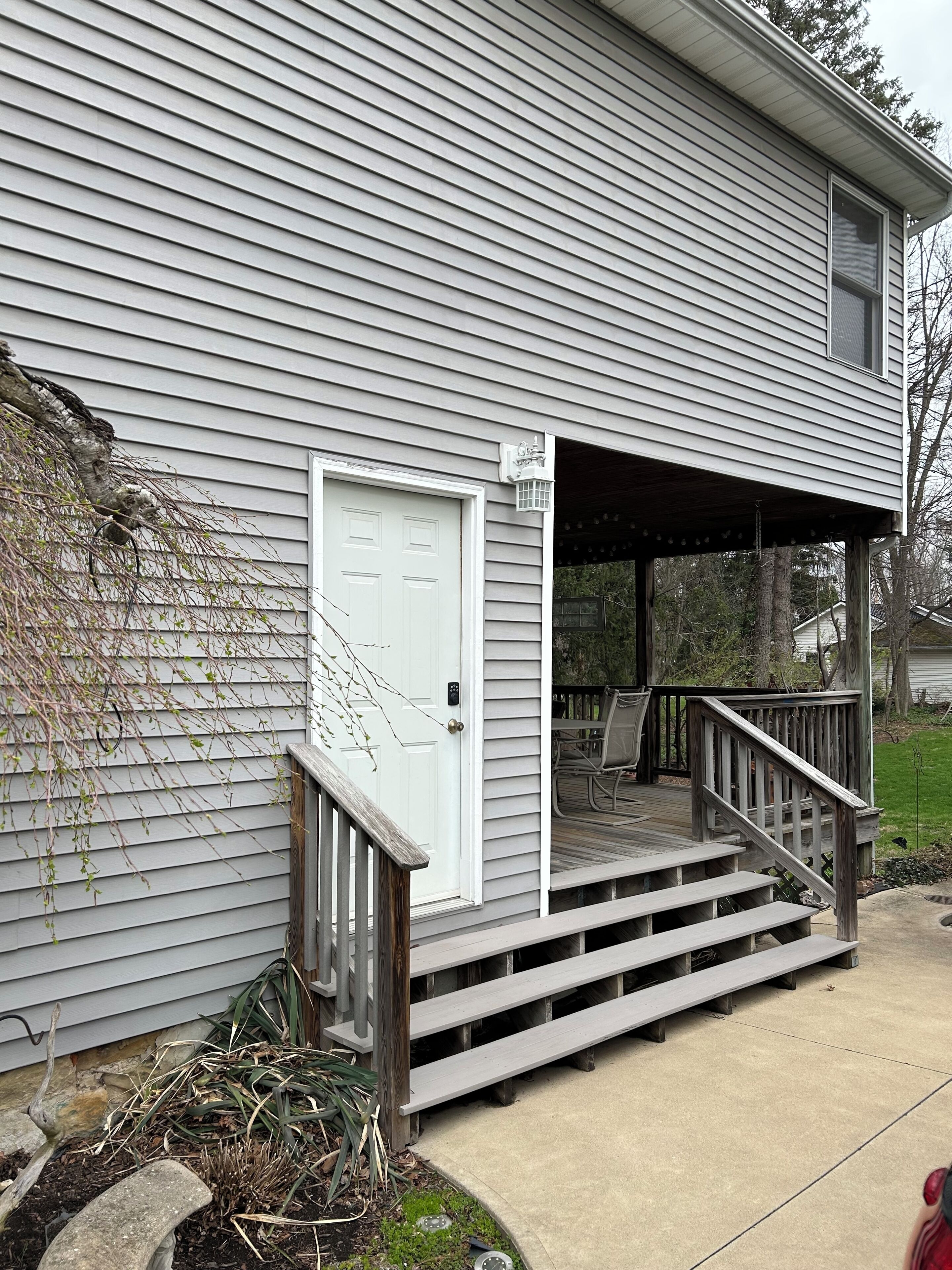 A residential house with a front porch, a door, and a small deck.