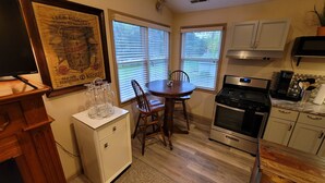 Una cocina con una mesa de comedor, sillas, estufa, armarios y un televisor.