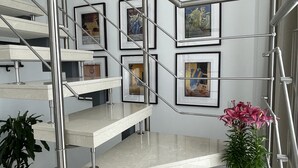Un escalier moderne avec des rampes en métal et des œuvres d’art encadrées accrochées aux murs.