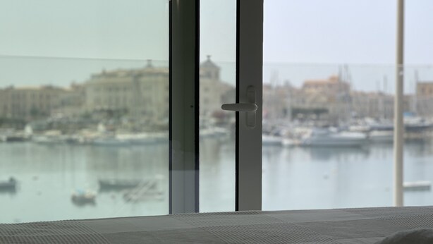 Une chambre d’hôtel avec vue sur un port de plaisance et sur les bâtiments situés de l’autre côté de l’eau.