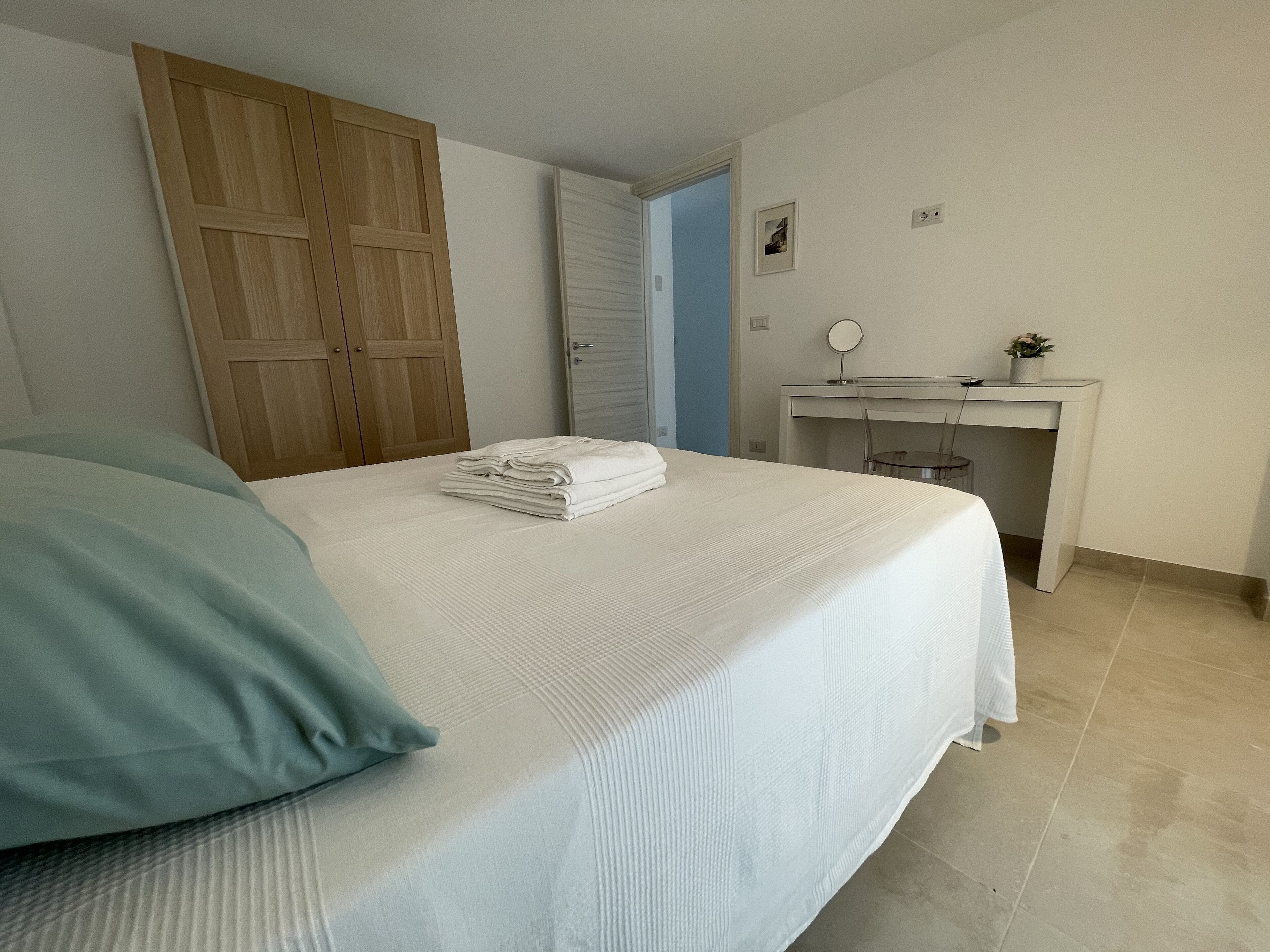 A bedroom with a bed, a desk, and a wardrobe.