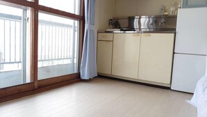 A kitchen with a large window, wooden floor, and a white refrigerator. - Hokusei Building 42 (Sapporo)